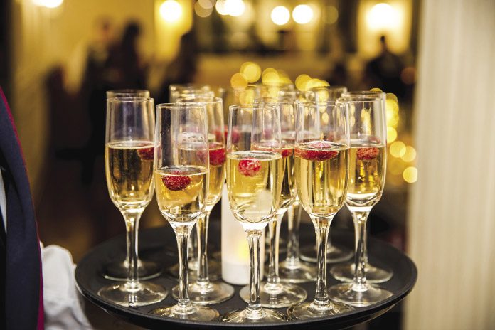 Champagne flutes filled with bubbly and a strawberry on a tray.